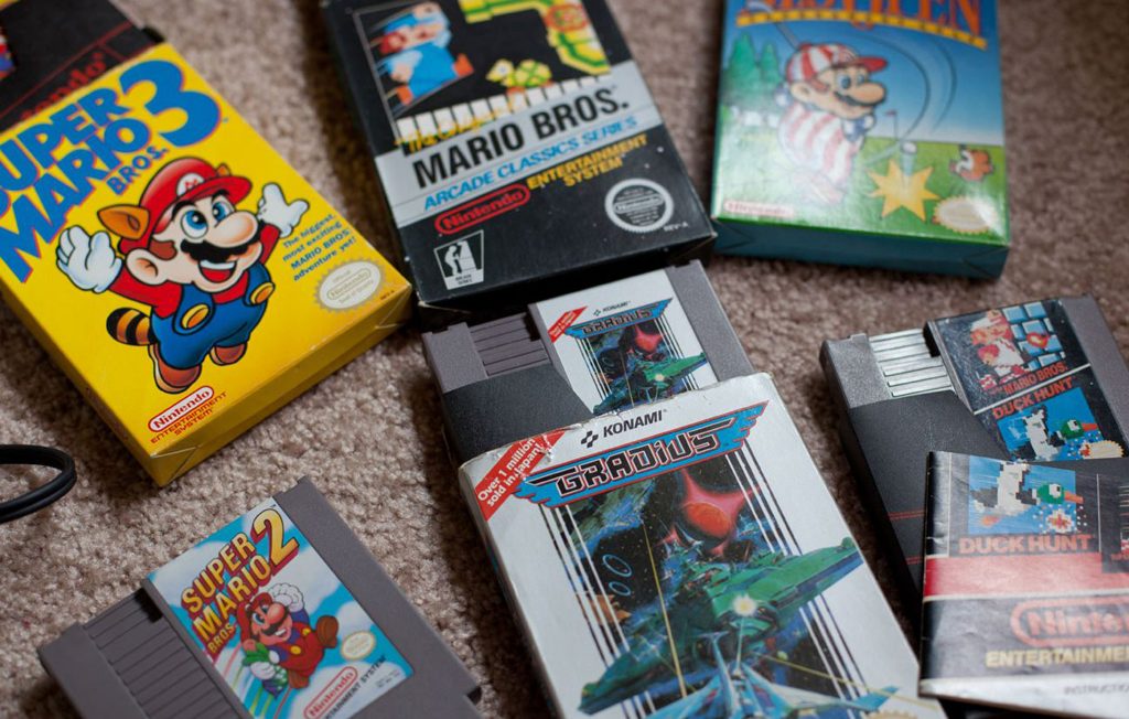 Boîtes et cartouches de jeux vidéo NES disposées au sol, avec notamment Super Mario Bros., Duck Hunt et Gradius.