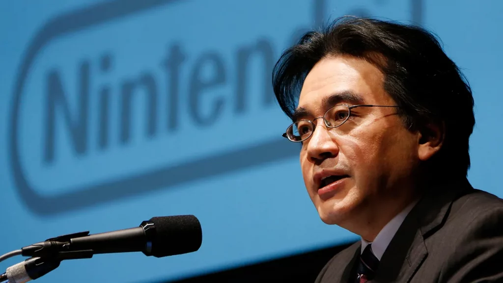 Satoru Iwata, président de Nintendo, s’exprimant devant un micro lors d’une conférence.